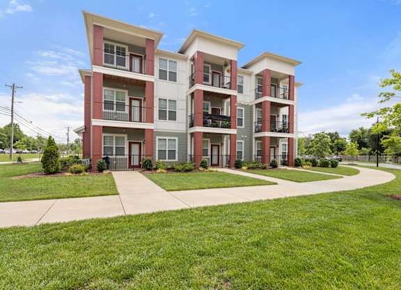 A red and white apartment building with a green lawn in front.