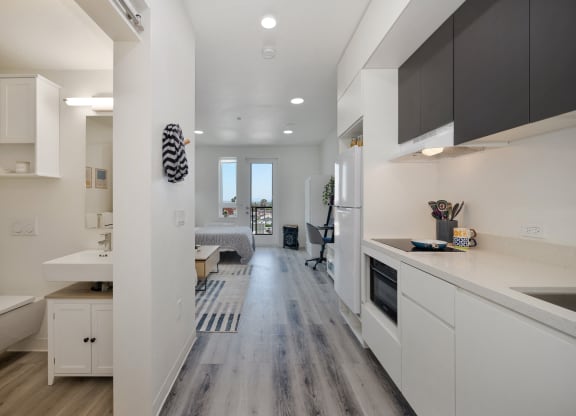 a kitchen and living room with white cabinets and wood floors