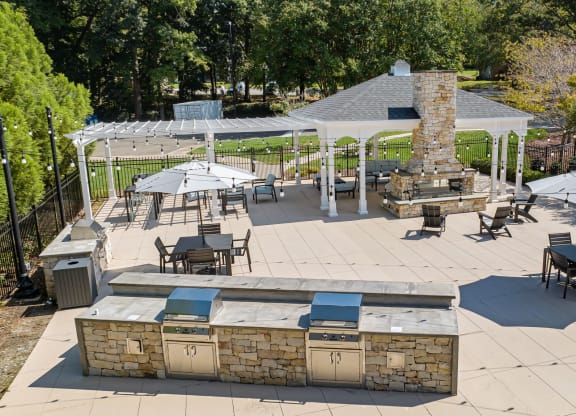 a patio with a grill and tables with umbrellas at View at Lake Lynn, North Carolina, 27613