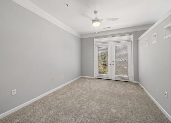 a bedroom with a ceiling fan and french doors