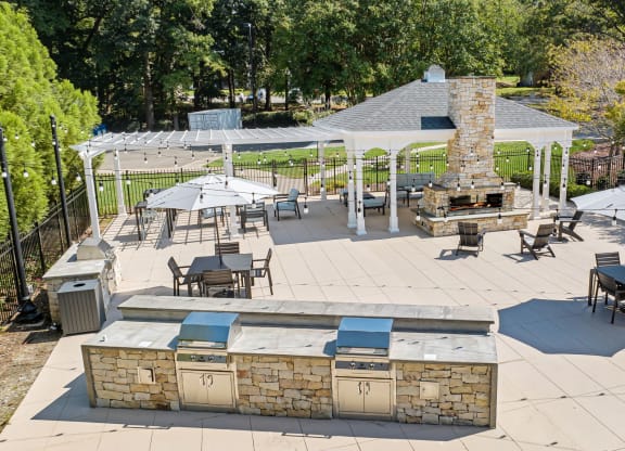 a patio with a grill and tables with umbrellas at View at Lake Lynn, Raleigh, 27613