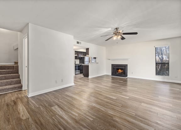 an empty living room with a ceiling fan and a fireplace