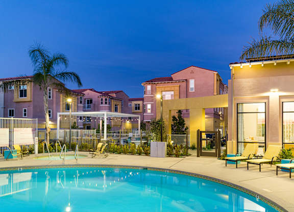 A swimming pool in front of a building with a yellow building to the right.