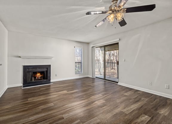an empty living room with a fireplace and a ceiling fan