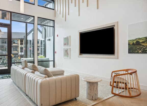 a living room with a white couch and a television on the wall