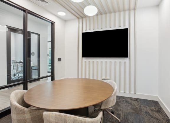 a conference room with a table and chairs and a tv on the wall