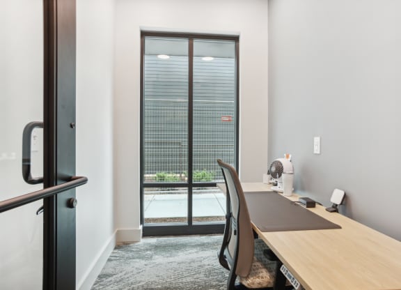 an office with a desk and a door to a balcony
