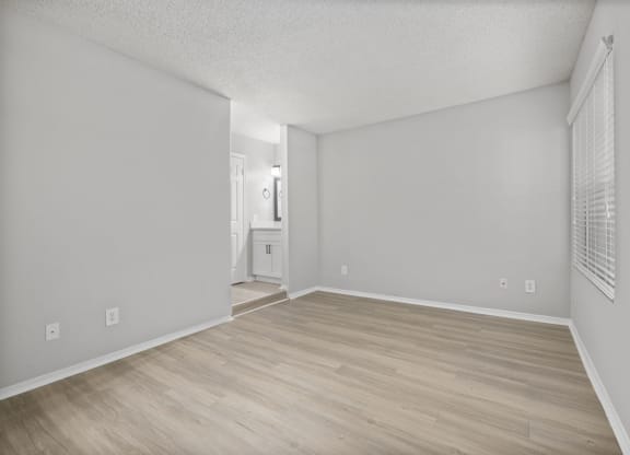 an empty living room with wood flooring and white walls