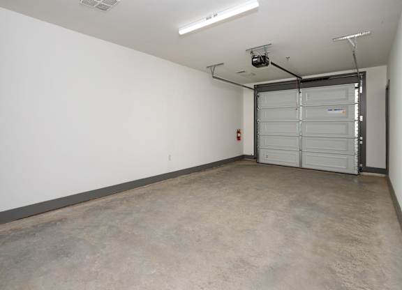 A large empty room with a white wall and a closed white door at the end.