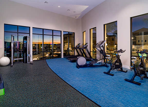 A gym with a view of the sunset through the windows.