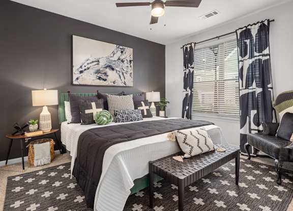 A bedroom with a large bed, a chair, and a painting on the wall.