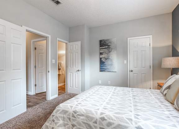 A bedroom with a large bed and a painting on the wall.
