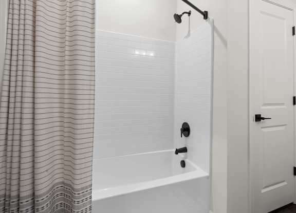 A white bathroom with a shower curtain and a white door.
