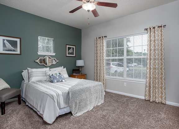 A bedroom with a bed, nightstand, and window.