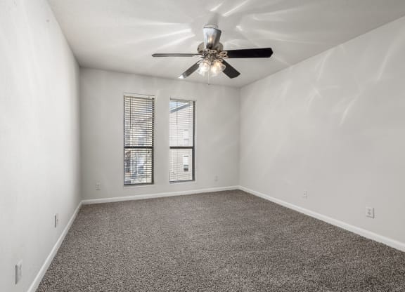 an empty living room with a ceiling fan and a window