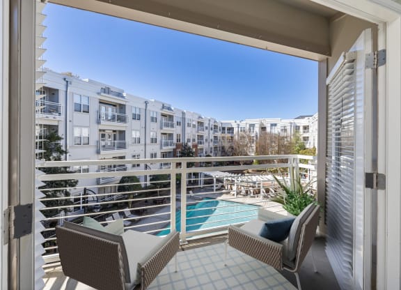 a balcony with two chairs and a view of a pool