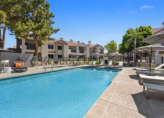 A large swimming pool surrounded by lounge chairs and umbrellas.