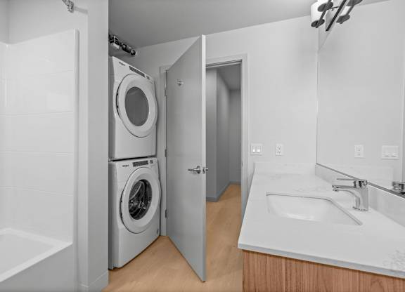 A white bathroom with a washer and dryer in the doorway.