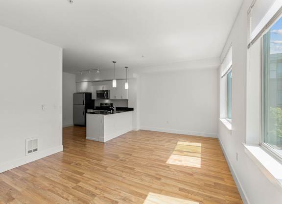 Open concept living room and kitchen with wood flooring at Six Oaks Apartments, Bothell, WA 98011