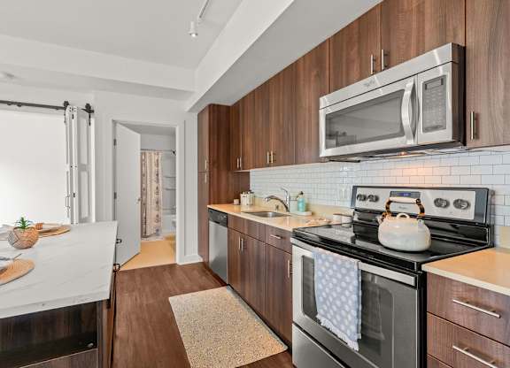 Galley kitchen with wood cabinets and white subway tile at Six Oaks Apartments, Bothell, Washington