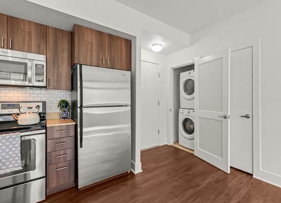 Kitchen with wood cabinets and stacked washer dryer closet at Six Oaks Apartments, Bothell