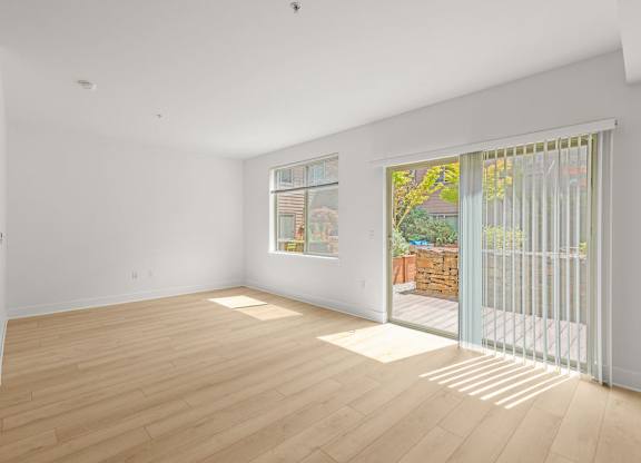 Empty living room with patio access and hardwood floors at Six Oaks Apartments, Bothell