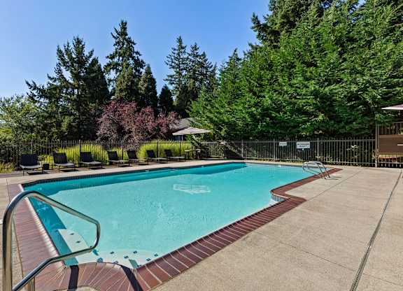 Outdoor swimming pool with lounge chairs and fencing at Scout Apartments, Kirkland