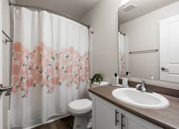 Bathroom with floral shower curtain and wood vanity at Hidden River Townhomes Apartments, Kirkland, Washington