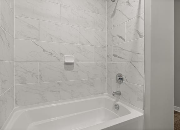 A white bathtub with a shower head and a faucet.