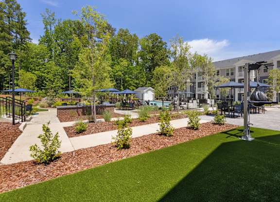 A sunny day at a park with a grassy area and trees.