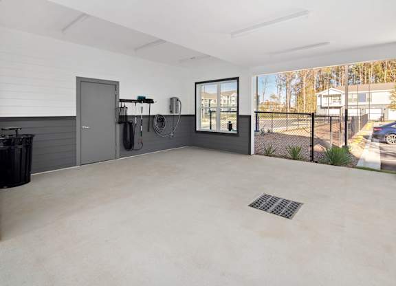 A spacious garage with a concrete floor and a black trash bin.