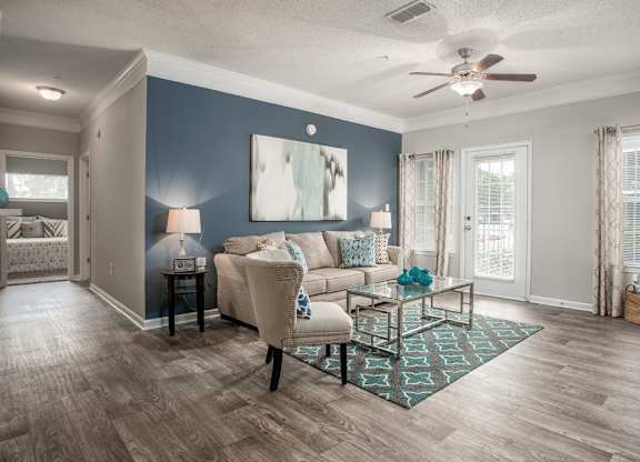 A living room with a beige couch, a coffee table, and a ceiling fan.