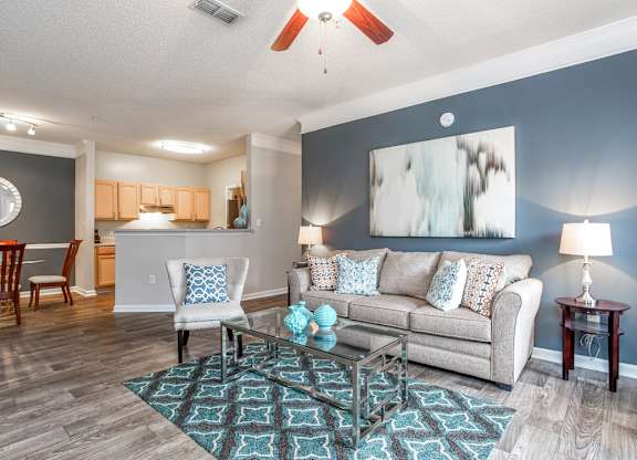 A living room with a couch, chairs, and a rug.