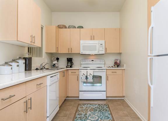 A kitchen with white appliances and wooden cabinets.