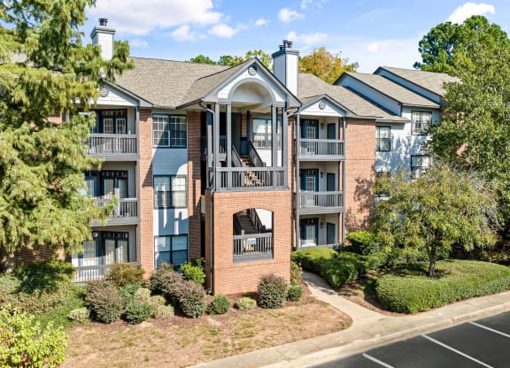 an apartment building with brick exterior and balconies with trees at View at Lake Lynn, Raleigh