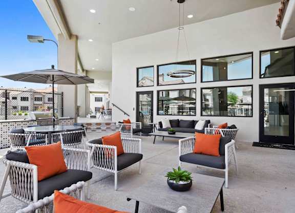A patio with black and white furniture and orange pillows.