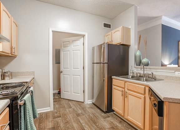 A kitchen with wooden cabinets and a black refrigerator.
