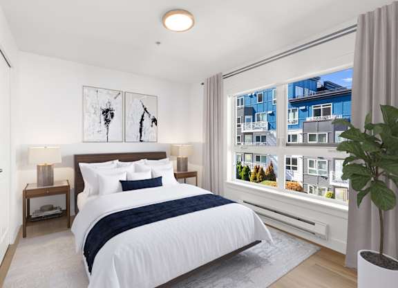 A bedroom with a large bed and a view of a cityscape through the window.