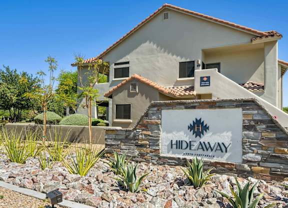 A house with a sign that says HIDEAWAY in front of it.