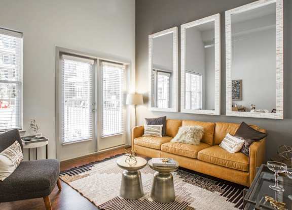 A living room with a couch, chair, and mirrors.