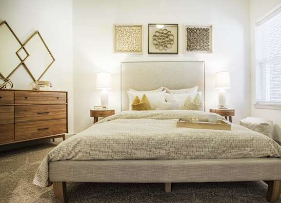 A bedroom with a large bed, a wooden dresser, and a mirror.