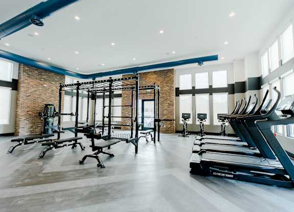 the gym has treadmills and other exercise equipment and windows