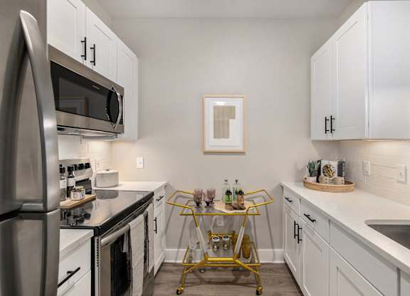 an apartment kitchen with stainless steel appliances and white cabinets