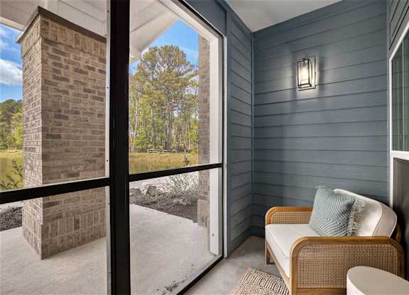 a screened porch with a couch and a table and a brick wall