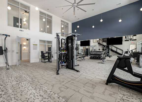a gym with weights and cardio equipment in a building with large windows
