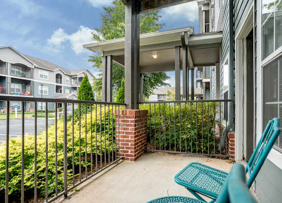 A patio with a blue chair and a brick pillar.