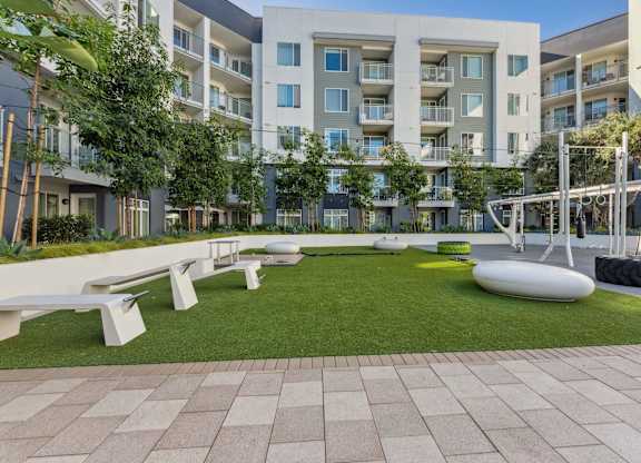 A modern apartment complex with a grassy courtyard and benches.