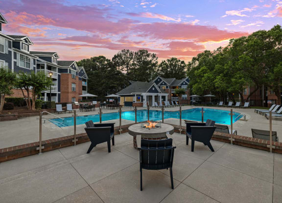 a swimming pool with a patio with chairs and a fire pit