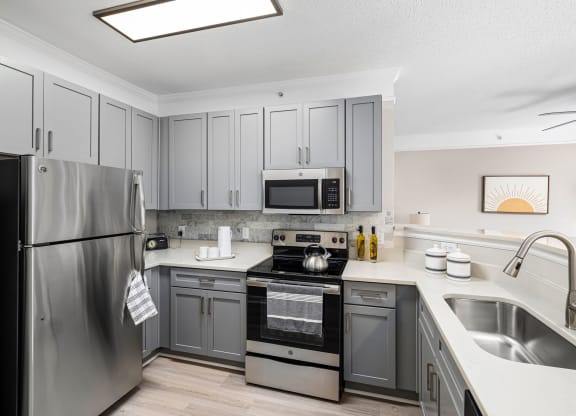 a kitchen with stainless steel appliances and gray cabinets at Mariners Crossing, Raleigh, NC