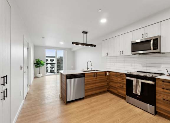 A modern kitchen with wooden cabinets and stainless steel appliances at Ion Town Center, Shoreline, WA 98133